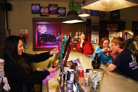 MSU students Bronwyn Rolph and Chris Zimny enjoy locally brewed beers at the Bozeman Brewing Company taproom, while bartender Mitzi Kuall pours a pint. Photo by Brent Zundel