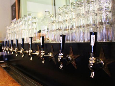 Pint glasses and growlers wait to be filled above the taps at Outlaw Brewing in Belgrade, Mont. Photo by Brent Zundel